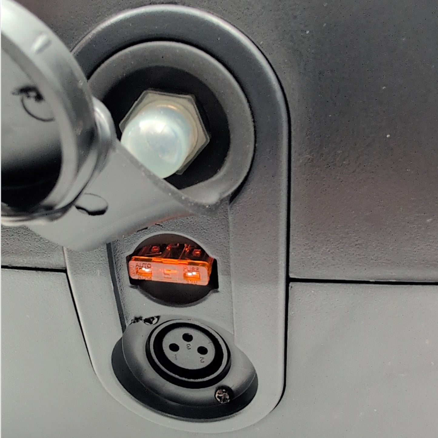 Cover lifted off of the front port. Shows the 3-pin XLR charging port, a 5 Amp Fuse, and the reset switch for the circuit breaker