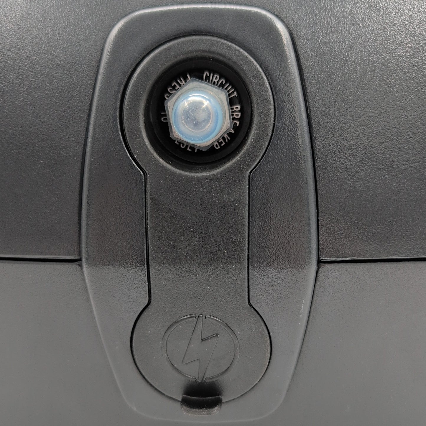 close up of charger port with cover on. Showing: 20 amp circuit breaker reset button