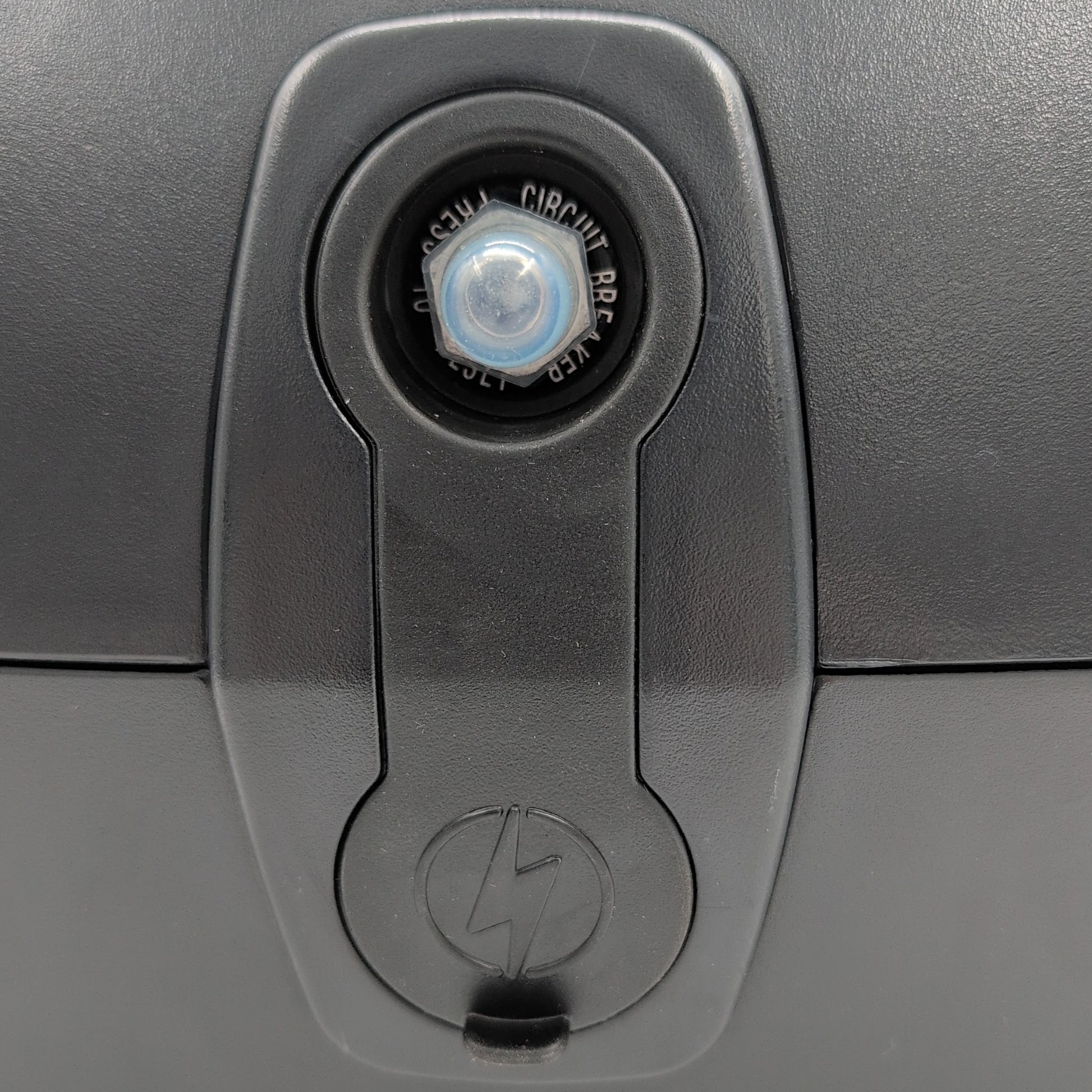 close up of charger port with cover on. Showing: 20 amp circuit breaker reset button